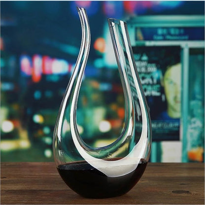 Glass wine decanter with red wine on a wooden surface with a blurred cityscape background