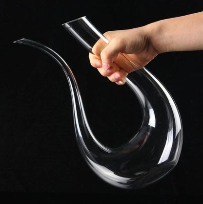 Clear glass decanter held by a hand against a black background