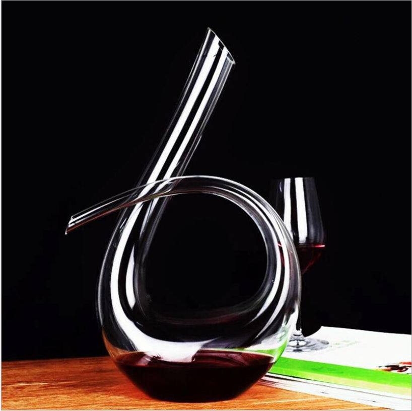 Glass wine decanter with a glass of red wine on a wooden surface.