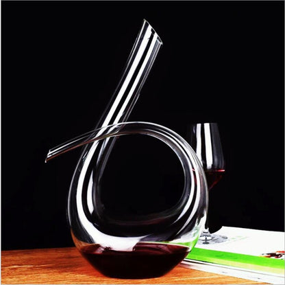 Glass wine decanter with a glass of red wine on a wooden surface.