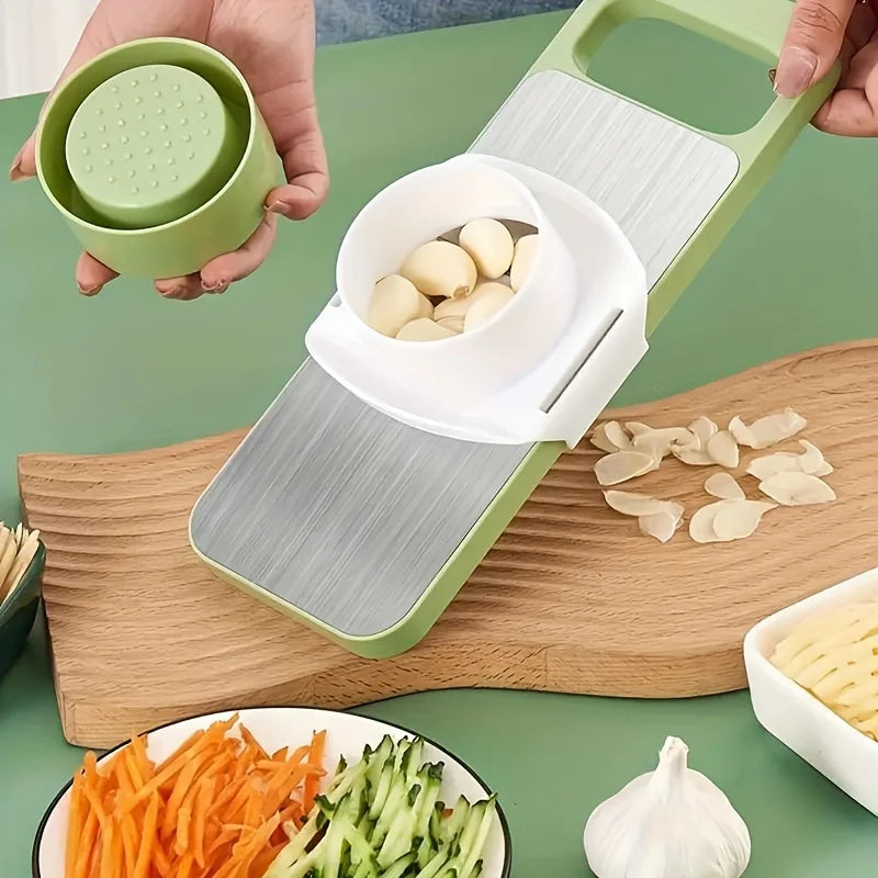 Vegetable chopper with garlic and sliced vegetables on a green surface