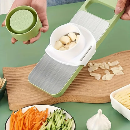 Vegetable chopper with garlic and sliced vegetables on a green surface
