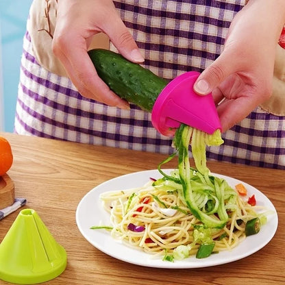 Person using a pink vegetable spiralizer to create zucchini noodles on a plate of pasta.