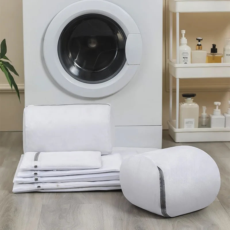 White laundry basket, folded white towels, and a washing machine in a laundry room.