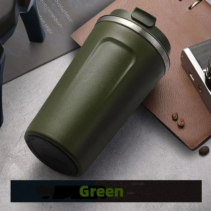 Green insulated tumbler on a gray surface with coffee beans and a brown leather case.