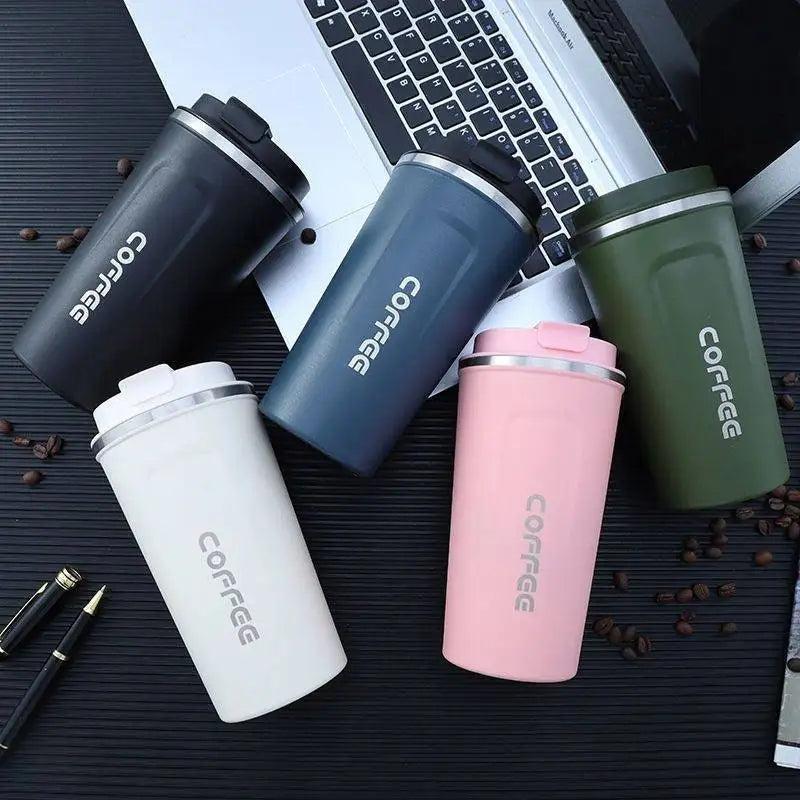 Five colorful coffee tumblers with 'COFFEE' text on a dark surface with a laptop.