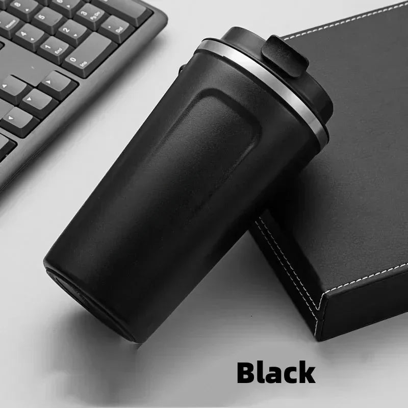Black travel mug on a desk with a keyboard and mouse pad in the background.