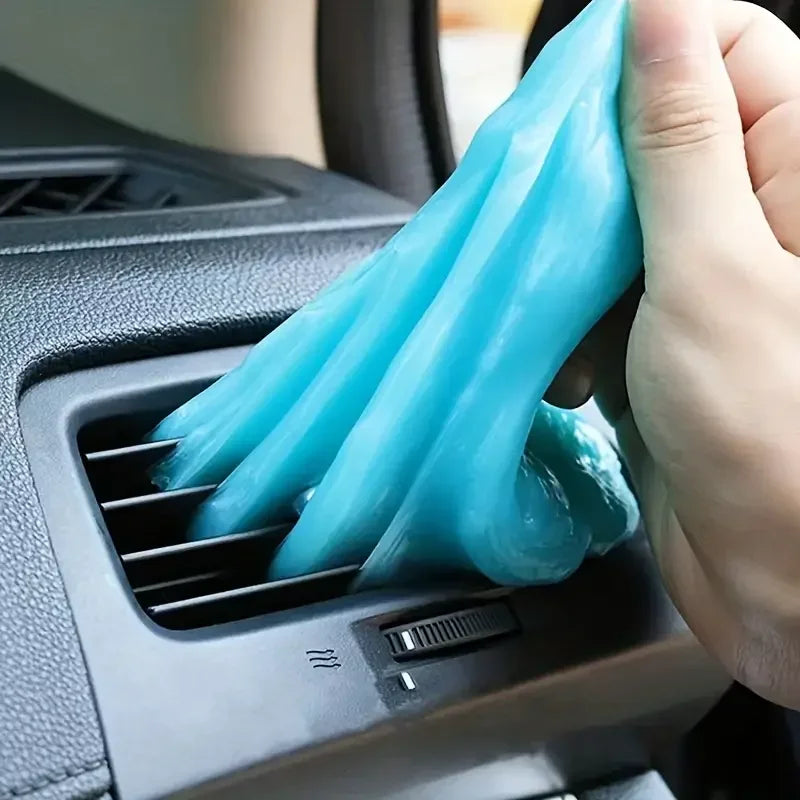 Hand using a blue cleaning cloth to clean a car's air vent.