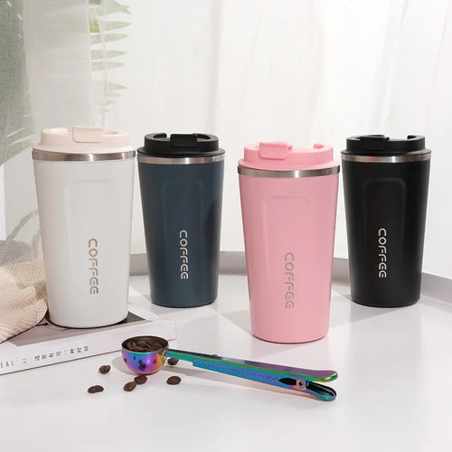 Four stainless steel coffee tumblers in white, navy, pink, and black on a light surface with coffee beans and a scoop.