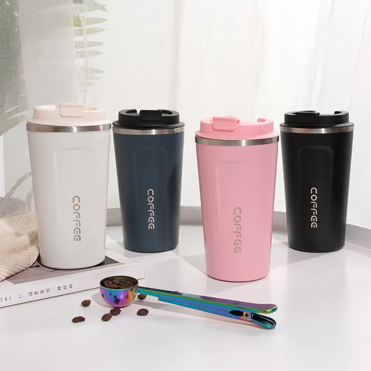 Four stainless steel coffee tumblers in white, navy, pink, and black on a light surface with coffee beans and a scoop.