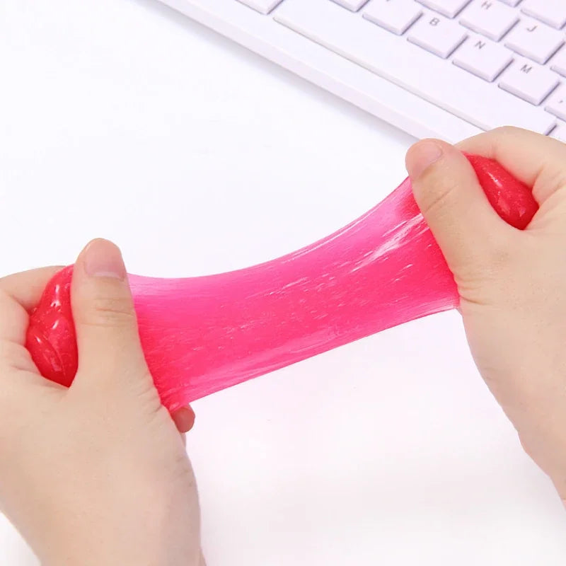Pink slime being stretched by hands with a white keyboard in the background