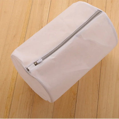 White mesh laundry bag with a zipper on a wooden floor