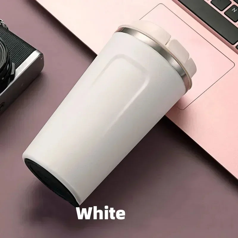 White tumbler on a desk with a camera and laptop in the background