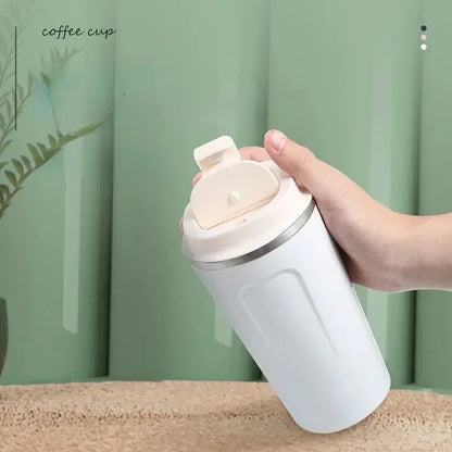 Hand holding a white insulated coffee cup with a green background